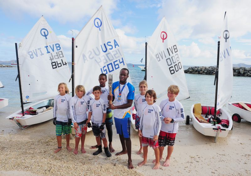 Thad Lettsome (left side of baton); Glenford Gordon (holding baton) and local optimist sailors with the Queen's Baton. 